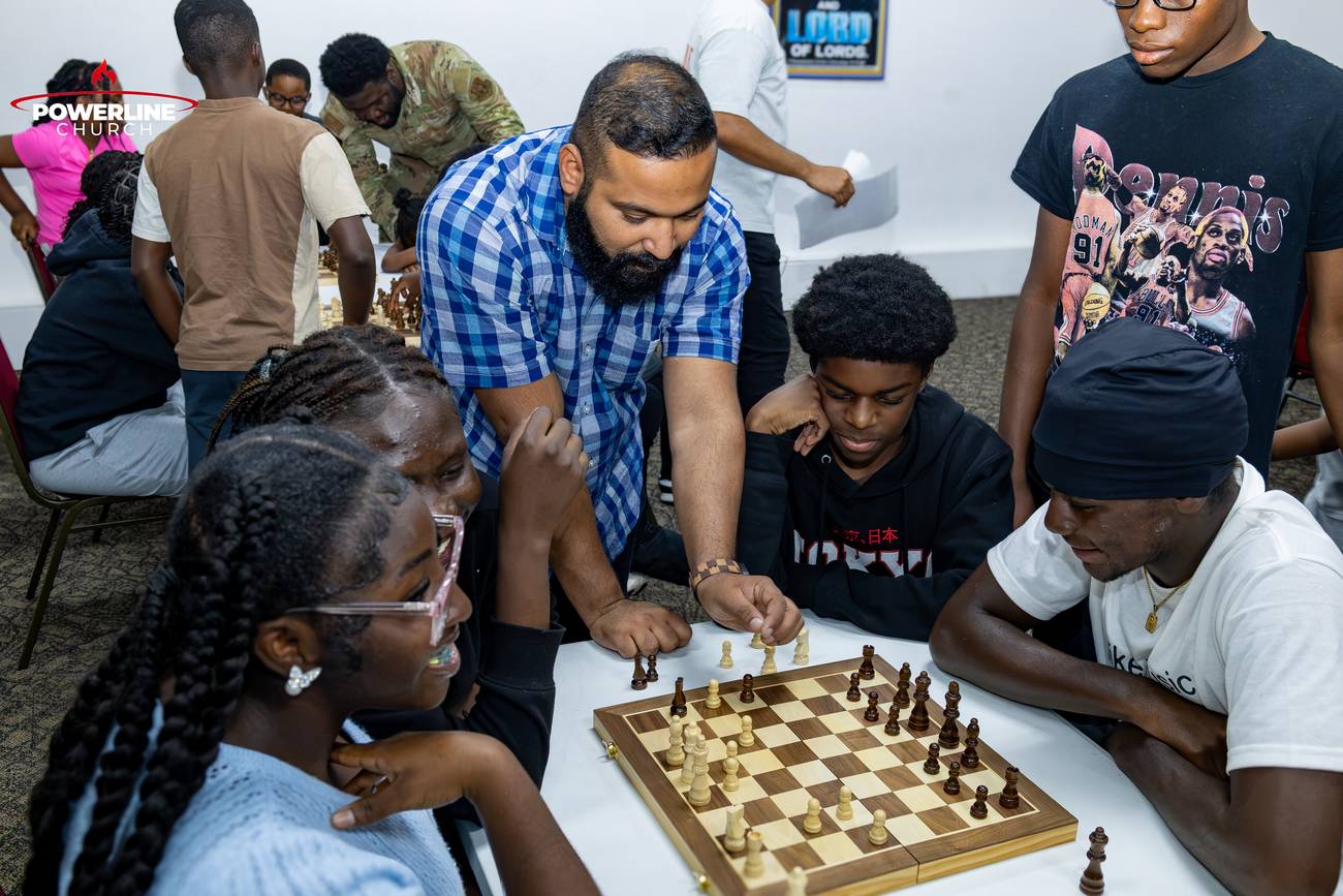 A leader teaching chess to young people at Powerline Church